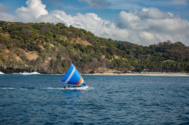 Pequeño velero flota en el agua con impresionantes vistas a la montaña.