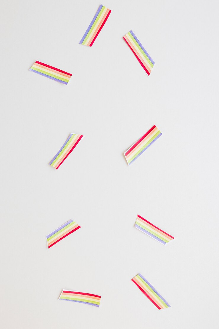 Foto gratuito pequeños arco iris de papel esparcidos sobre la mesa.