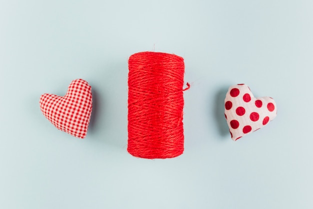 Pequeños corazones brillantes suaves con cuerda rollo en mesa