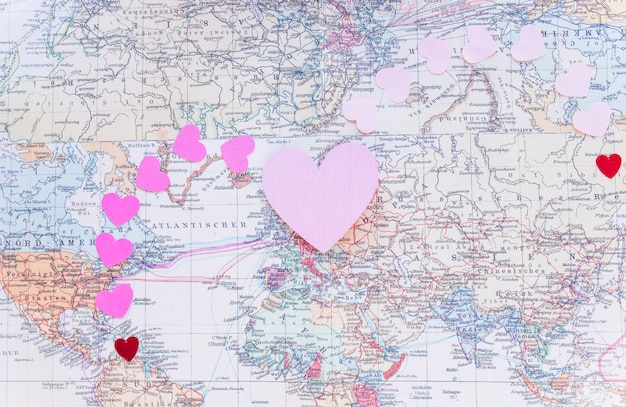 Pequeños corazones de papel de colores en el mapa del mundo