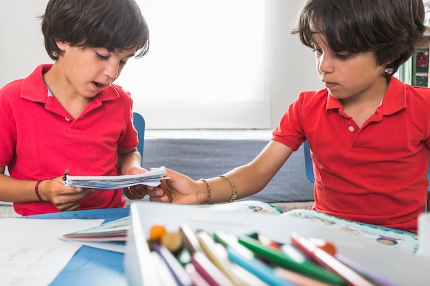 Pequeños gemelos haciendo artesanías de papel juntos