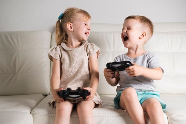 Pequeños hermanos jugando juegos digitales con joystick