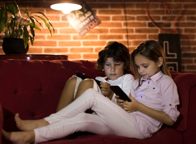 Pequeños hermanos jugando en sus dispositivos electrónicos