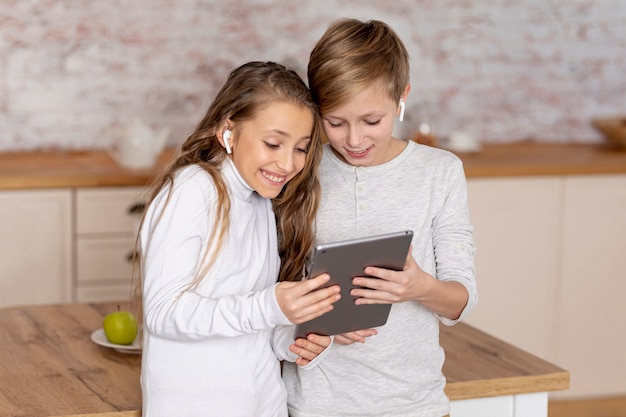 Foto gratuita pequeños hermanos que miran juntos en una tableta