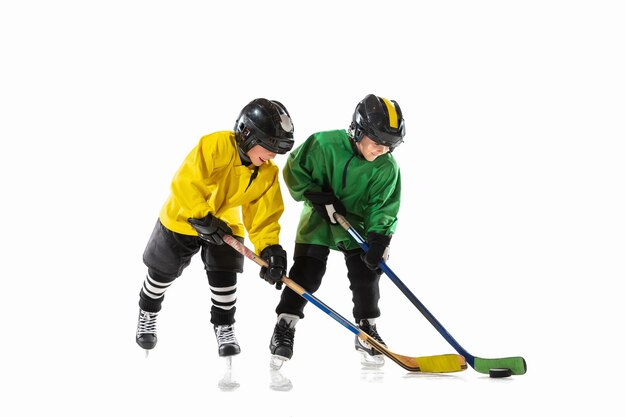 Pequeños jugadores de hockey con los palos en la cancha de hielo y fondo blanco.