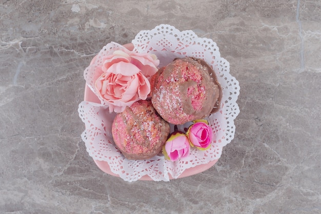 Foto gratuita pequeños pasteles y corolas de flores en un cuenco cubierto de tapete sobre mármol