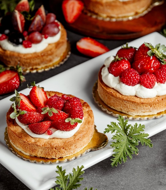 pequeños pasteles decorados con crema de fresa y frambuesas