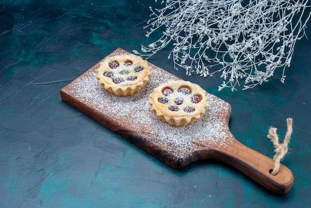 Foto gratuita pequeños pasteles deliciosos con azúcar de frutas en polvo sobre un escritorio azul, pastel de galletas de azúcar dulce