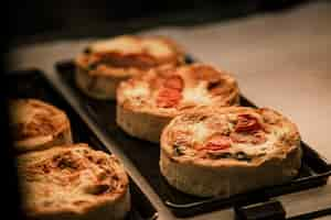 Foto gratuita pequeños pasteles de hojaldre con verduras y quiches de carne en la ventana de un café