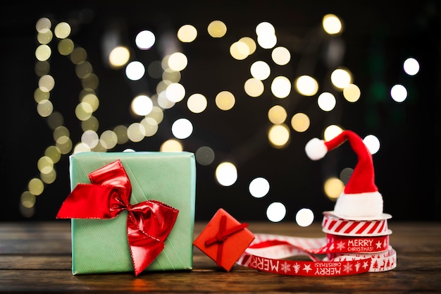 Pequeños regalos junto a cintas y gorro navideño.