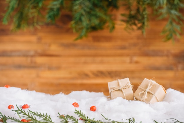 Foto gratuita pequeños regalos en la nieve con ramas de coníferas.