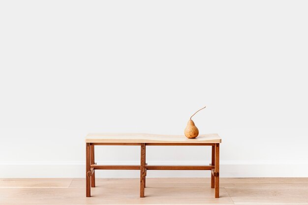 Pera marrón en un banco de madera en una habitación blanca