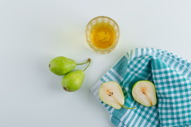 Peras con bebida en blanco y superficie de toalla de cocina, vista superior.