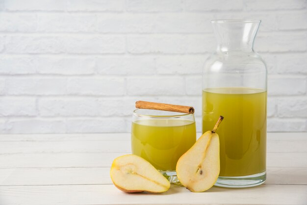 Peras con un frasco de vidrio de jugo y ramas de canela