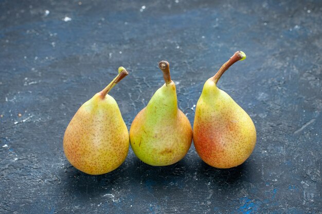 Peras frescas y melosas frutas enteras maduras y dulces forradas en el escritorio oscuro