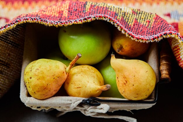 Peras y manzanas maduras en canasta