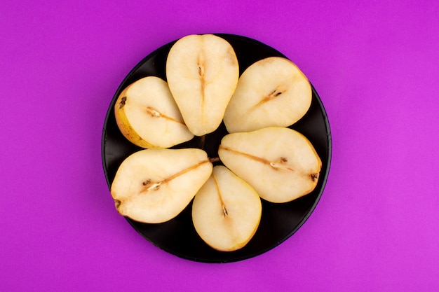 Foto gratuita peras redondas en forma de frutas maduras frescas dentro de la placa negra sobre un escritorio morado