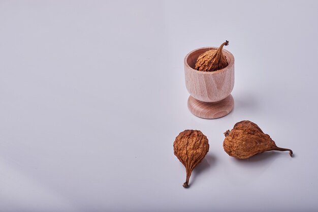 Peras secas en una taza de madera y sobre el fondo gris