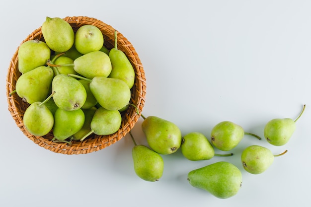 Foto gratuita peras verdes en una cesta en mesa blanca