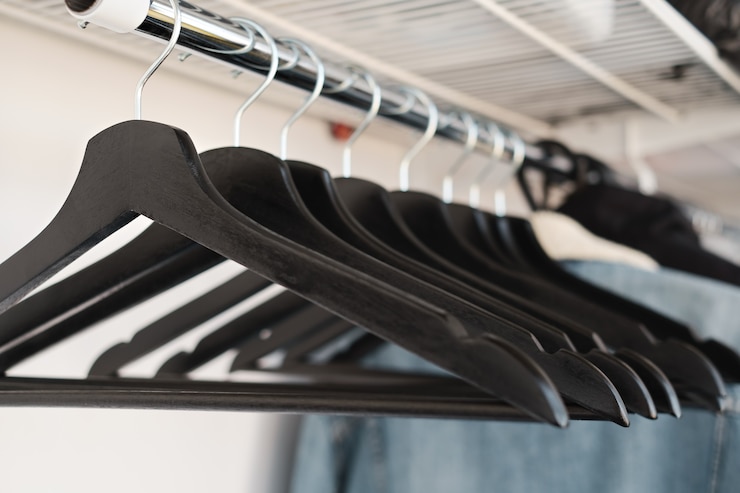 Foto gratuito perchas de ropa negra en un estante en una tienda de ropa, primer plano, enfoque selectivo. moda, liquidación en tienda. banner de blog