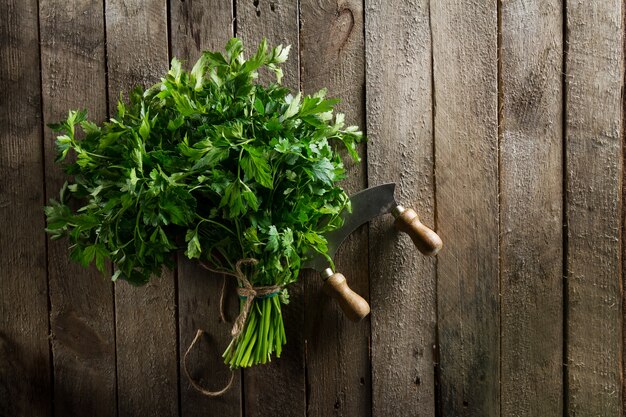 Perejil vibrante colorido fresco con el cuchillo en la tabla de madera. Verano, Primavera, Vida Sana o Concepto de Detox.