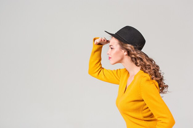 El perfil de la chica emocional con sombrero en la pared gris