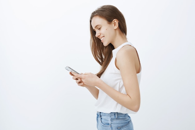 Perfil de chica joven moderna y elegante con smartphone y sonriendo feliz