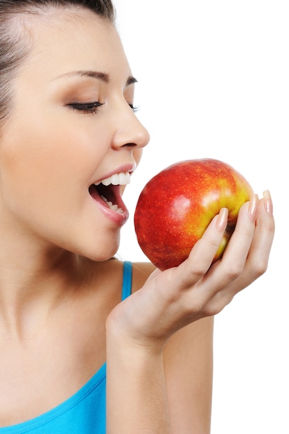 Perfil de hermosa niña comiendo una manzana - aislado en blanco