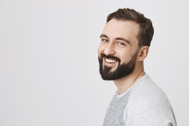 Perfil de hombre barbudo con nuevo corte de pelo, sonriendo