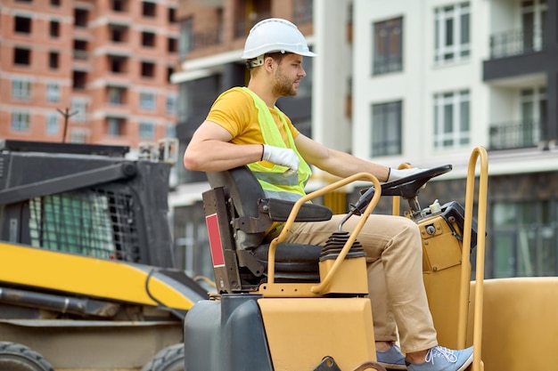 Foto gratuita perfil de hombre sentado al volante de la excavadora