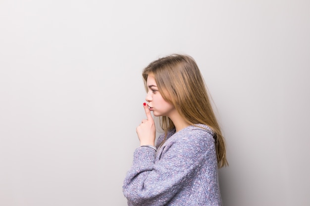 Perfil de una joven adolescente con gesto de silencio y presentación al lado aislado