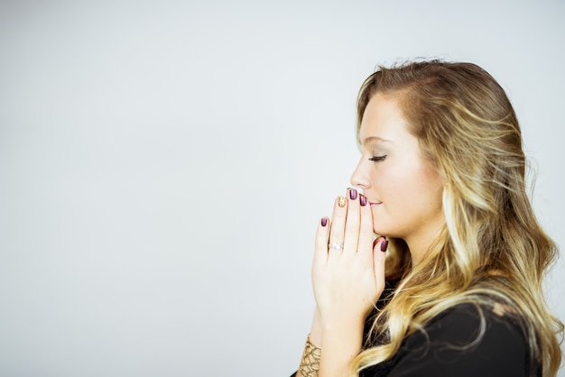 Foto gratuita perfil lateral, de, un, rezando, mujer rubia, contra, un, blanco