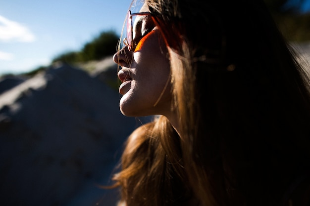 Perfil de mujer bonita en gafas de sol rojas