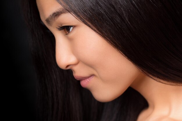 Perfil de primer plano de dama asiática con pelo largo y negro posando en el estudio.
