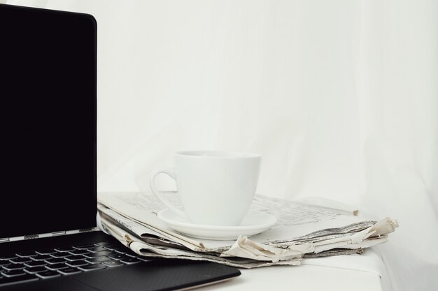 Periódico con taza de café y laptop