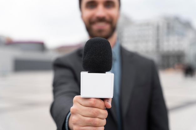 Periodista de vista frontal sosteniendo un micrófono
