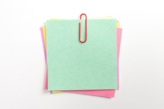 Perno de papel colorido de la nota con los clips de papel rojos y aislado en blanco.