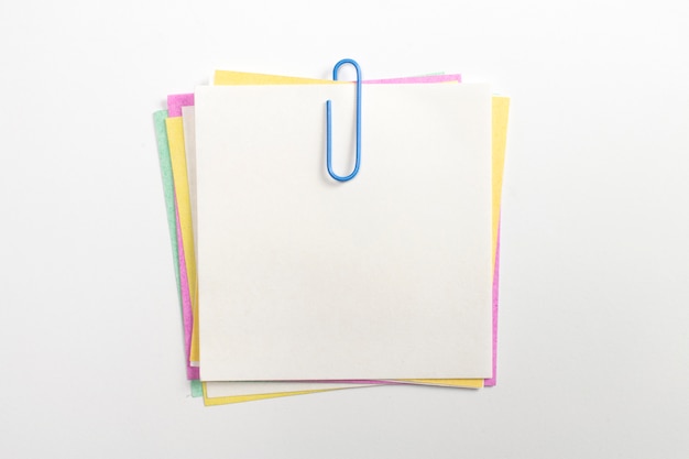 Perno de papel de nota colorido con clips de papel azul y aislado en blanco.