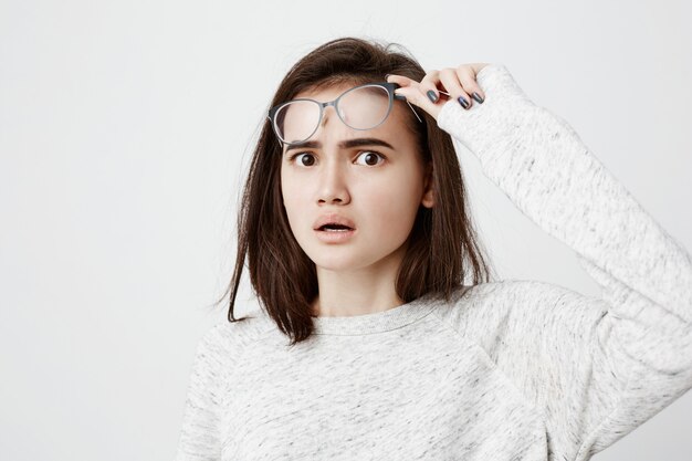 perpleja confundida hembra joven con cabello lacio y oscuro sintiéndose sorprendida, mirando