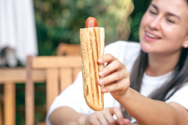 Foto gratuita un perrito caliente en las manos de una mujer en primer plano