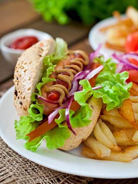 Perrito caliente con salsa de tomate mostaza y lechuga en la mesa de madera.