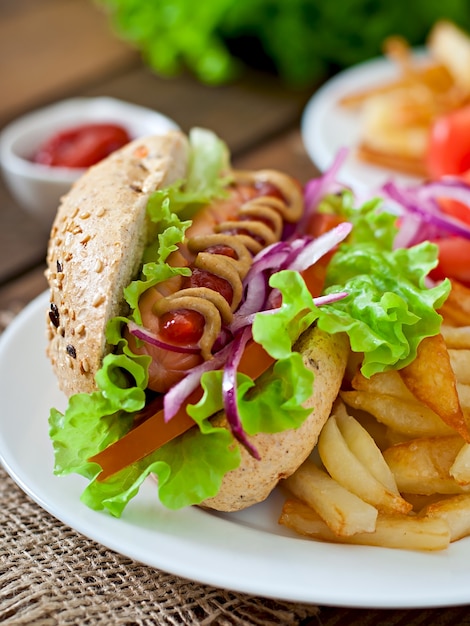 Perrito caliente con salsa de tomate mostaza y lechuga en la mesa de madera.