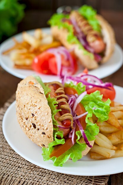 Perrito caliente con salsa de tomate mostaza y lechuga en la mesa de madera.