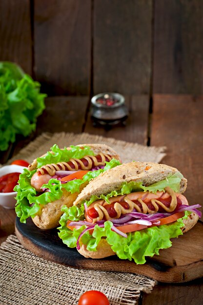 Perrito caliente con salsa de tomate mostaza y lechuga en la mesa de madera.