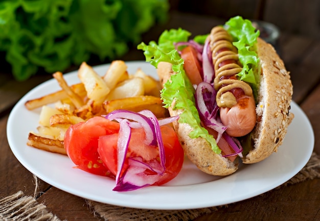 Perrito caliente con salsa de tomate mostaza y lechuga en la mesa de madera.