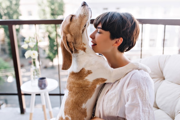 El perro beagle levantó la cabeza y posó con las patas en los hombros de la dueña.