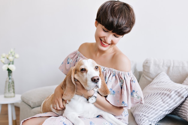 Perro beagle triste mirando a otro lado mientras hermosa chica con sonrisa encantadora posando