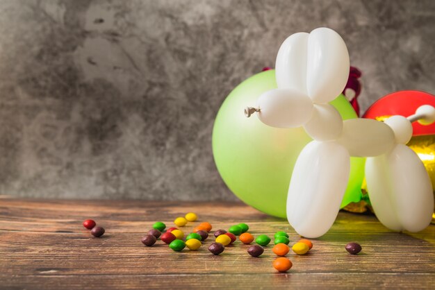 Perro blanco hecho con globos y caramelos coloridos en la mesa de madera