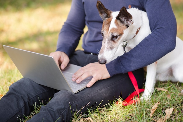 Perro con dueño y laptop en park