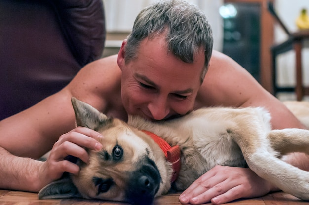 Perro fresco y hombre maduro que se divierte en el país. Sonriente, hombre, perro